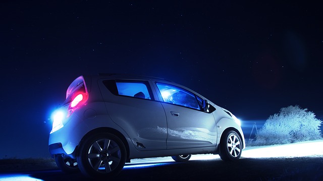 Biele auto v tme s hliníkovými diskami svieti prednými svetlami do diaľky